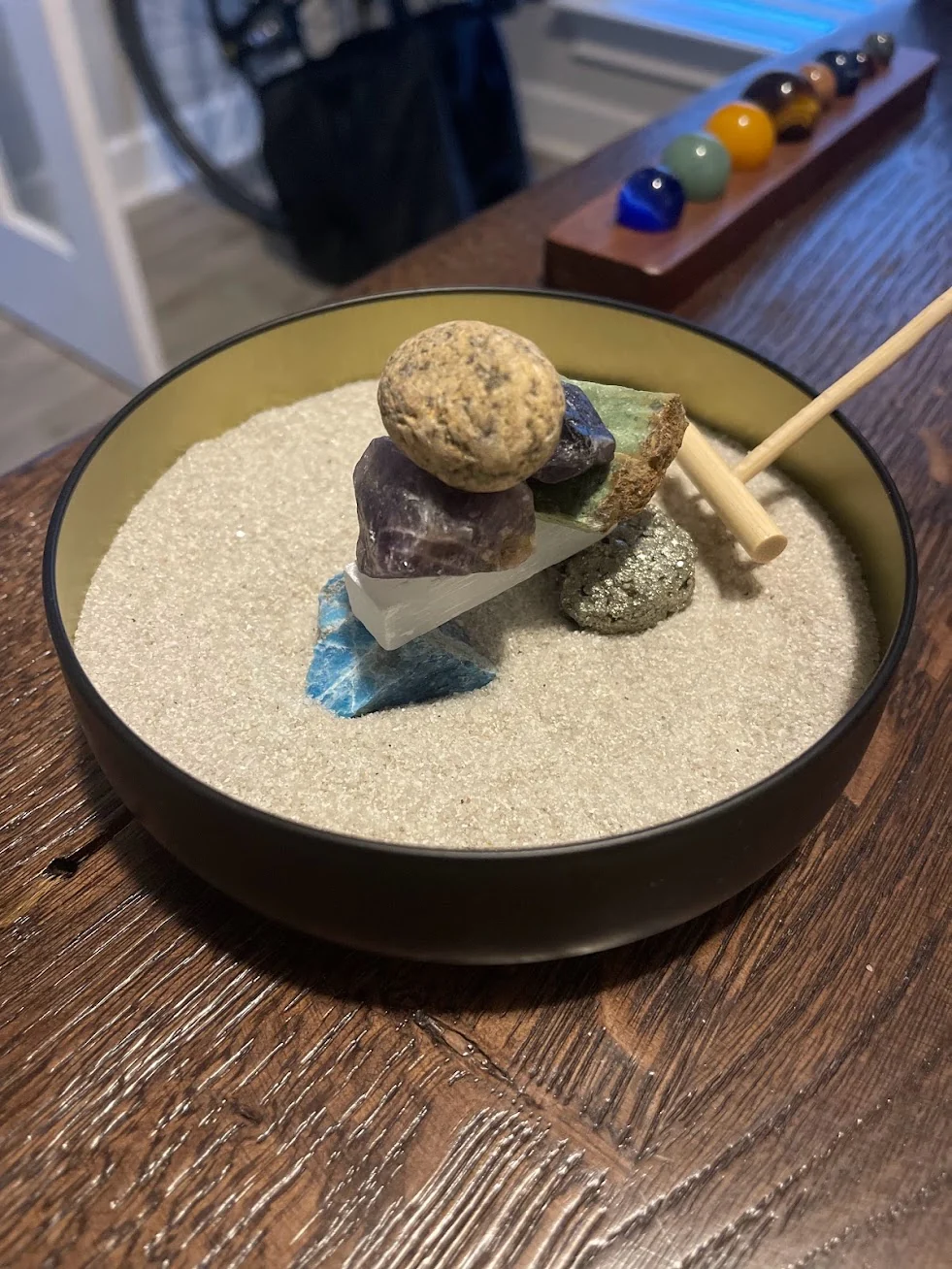 A small stack of colorful stones balanced in a tabletop sand garden