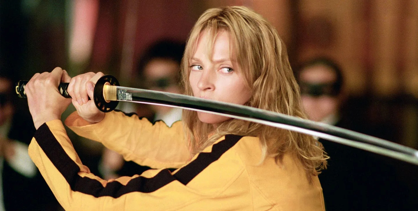 Uma Thurman as the Bride in Kill Bill, wearing her yellow-and-black suit and holding a sword