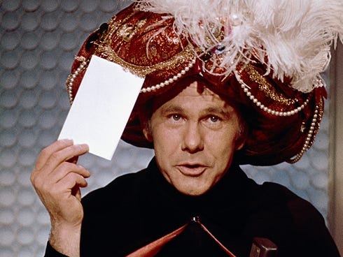 Carnac the Magnificent holding an envelope