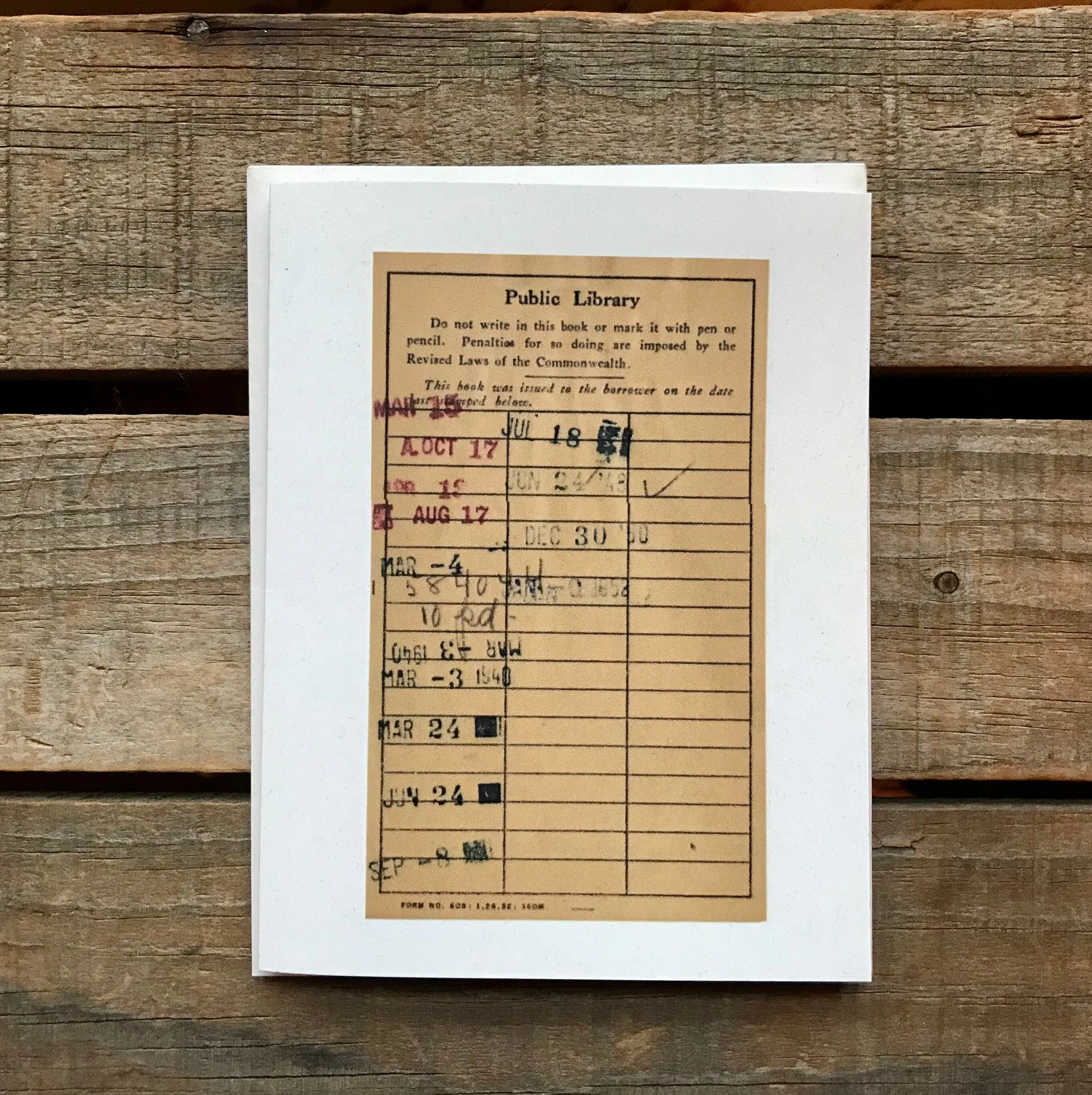 A vintage public-library checkout card with decades of stamped return dates