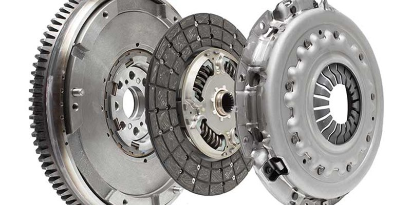 An automotive flywheel, clutch disc, and pressure plate shown as an exploded assembly